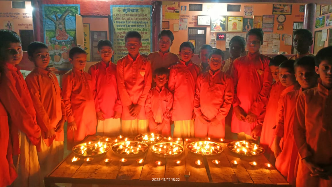 Students in orange robes participating in Diwali lamp lighting ceremony