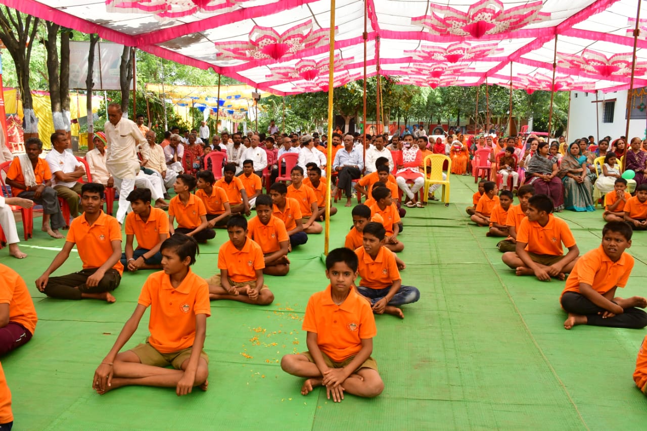 Students in organized outdoor assembly under colorful tent canopy